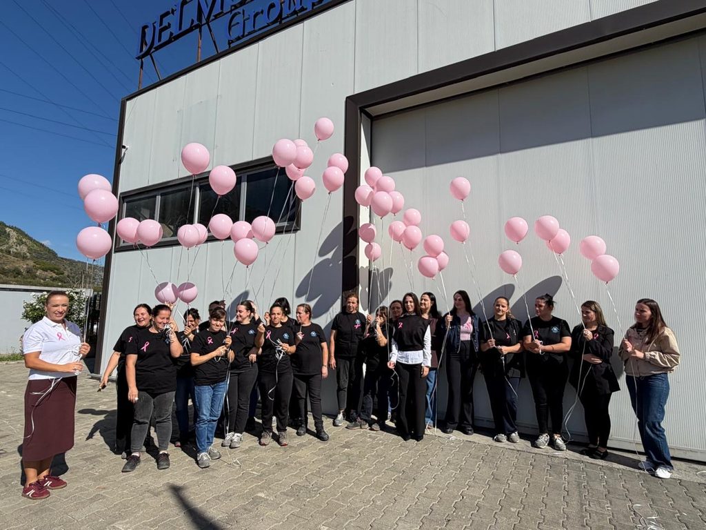 Un groupe de femmes tenant des ballons roses devant un bâtiment industriel.